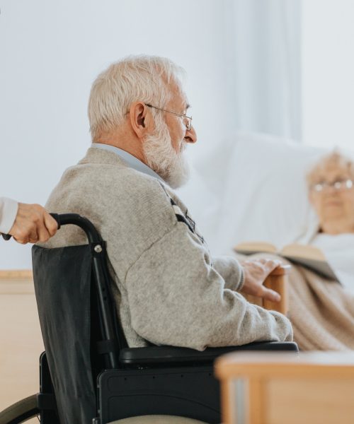 Senior man after stroke sits in a wheelchair at a nursing home